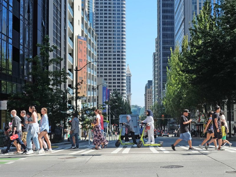 Pedestrians and scooters in a crosswalk on a sunny day