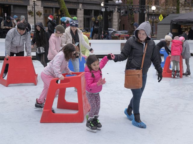 Family ice skating at Occidental Square for downtown holiday season.