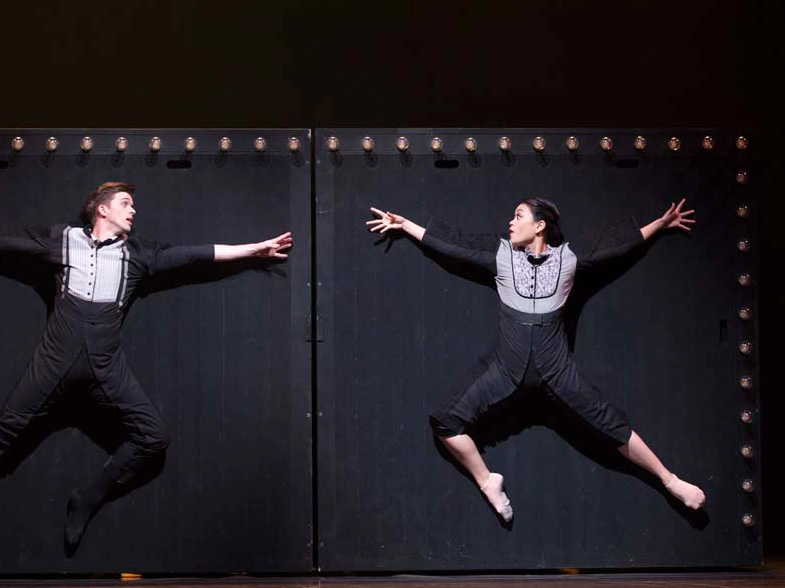 Two ballet dancers suspended mid jump, reaching out toward one another. Courtesy of Pacific Northwest Ballet.