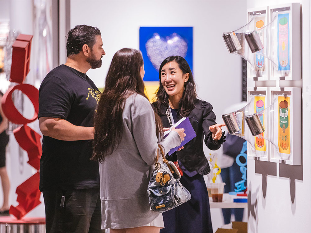 Visitors and artist/curator talking in front of an art piece. Courtesy of AMP.